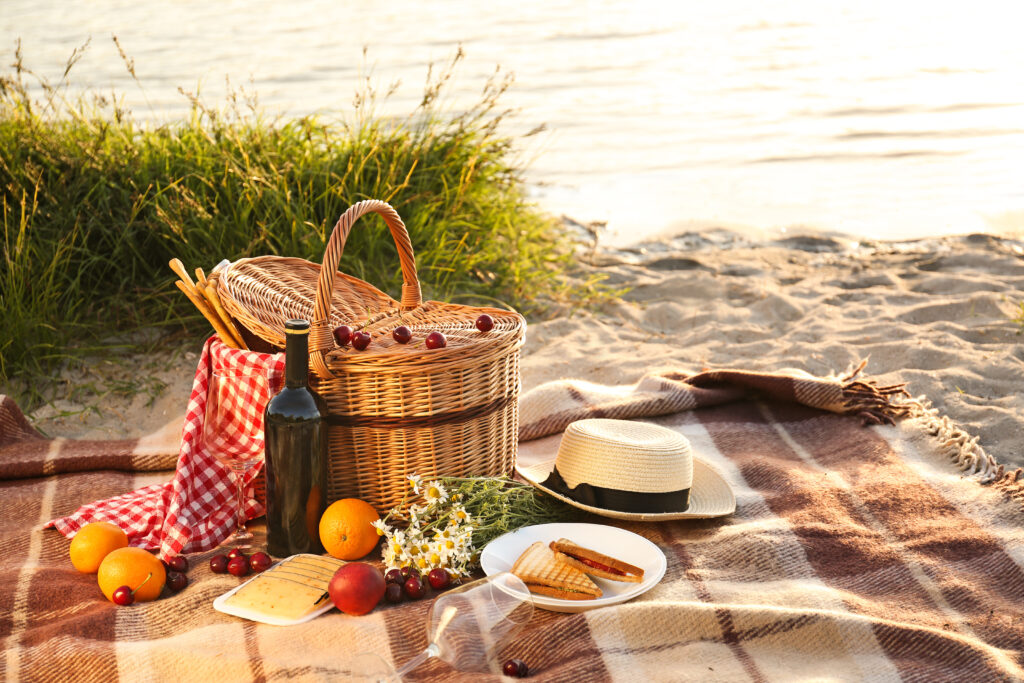 Un coș de picnic pentru o cină romantică pe plaja pe malul unui râu